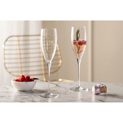 Zwei Sektgläser eines gefüllt mit Getränk und Beeren auf Tisch mit Dekoration