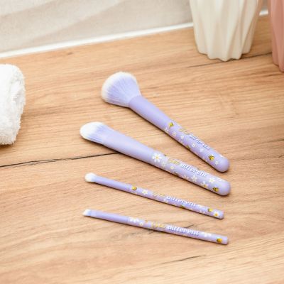 Vier lilafarbene Make-up-Pinsel im Bienen-Design, mit vier Pinseln auf einer hellen Holzfläche ausgelegt gezeigt.