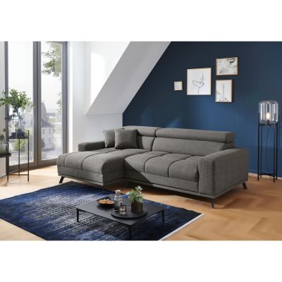 Dunkelgraue Eckcouch mit Longchair links im Bild, zwei Kissen und verstellbaren Kopfstützen vor einer dunkelblauen Wand