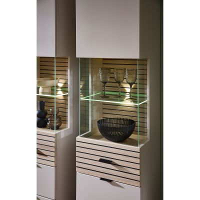Ein offenes, beleuchtetes Glasfach mit lamellenartiger Rückwand. Im Glasfach stehen Gläser und eine schwarze Schale, darunter weitere Dekoration.