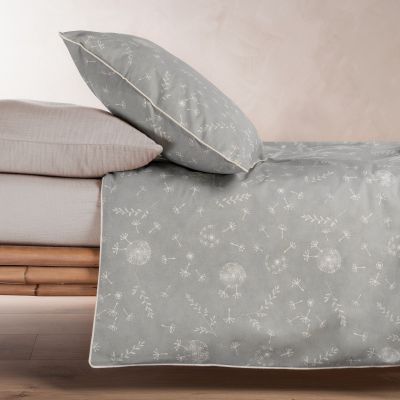 Aufgezogenes Bettwäsche-Set in Grün mit Pusteblumenmotiv auf einem Bett mit hellem Bettlaken