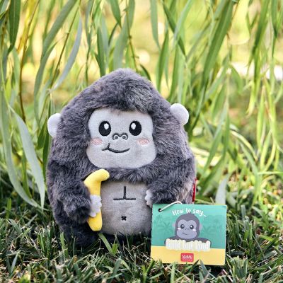 Graues Gorilla-Plüschtier mit gelber Banane, im Gras vor Pflanzen zusammen mit einem Produktanhänger dargestellt.