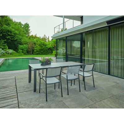 Mehrere Gartenstühle mit Armlehnen an einem rechteckigen Tisch auf einer Terrasse neben einem Pool