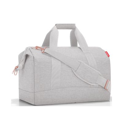 Reisetasche von Reisenthel, Modell Allrounder L, in sehr hellem Grau mit rosafarbenen Details, schräg von vorn mit Tragegriffen und Schultergurt.