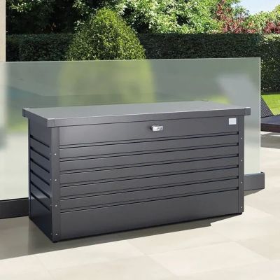 Anthrazitfarbene Auflagenbox aus Metall auf einer Terrasse im Garten vor Hecken