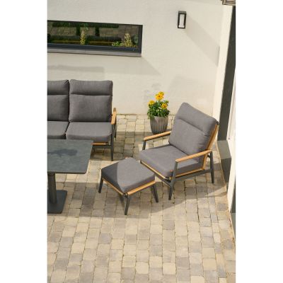 Hocker mit dunkelgrauem Polster, kombiniert mit passendem Sessel und Gartenset auf einer Terrasse