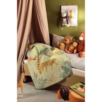 Babydecke Wildlife ist in einem Kinderzimmer zwischen Stofftieren drapiert und zeigt das hellgrüne Dschungelmotiv mit Leopard.