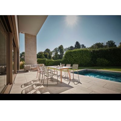 Mehrere Gartenstühle an Tisch auf Terrasse neben Pool und Grünfläche