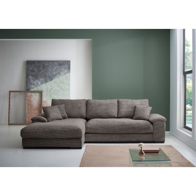 Braune Cord Wohnlandschaft mit Longchair links im Bild, tiefen Sitzflächen, gepolsterten Armlehnen und Zierkissen in einem hellen Wohnzimmer