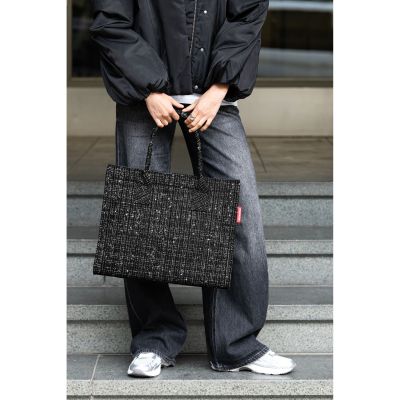 Shopper von Reisenthel, Modell Daily Shopper, in Schwarz mit Bouclé-Struktur, von einer Person an den kurzen Griffen getragen