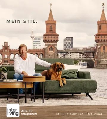 Schauspieler Henning Baum mit Hund auf Interliving Sofa am Flussufer vor Brücke – moderne Wohnstil-Inspiration bei Möbel Gruber