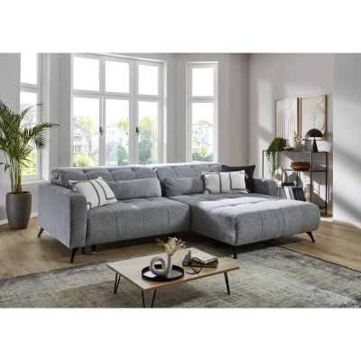 Helles Wohnzimmer mit großem Ecksofa in hellgrauem Stoff, dekoriert mit Kissen, Pflanzen und Couchtisch.