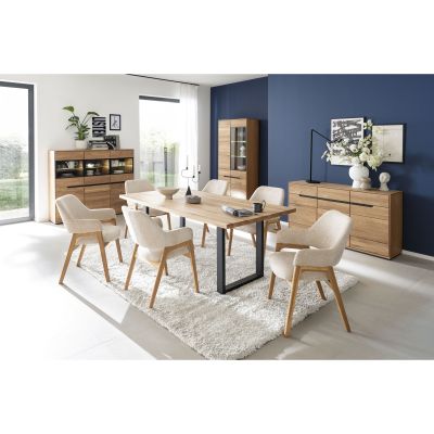 Helles Esszimmer mit einem Holztisch, sechs hellen Stühlen, einer Holzvitrine mit Glasfront, einer Anrichte und einer blauen Akzentwand im Hintergrund
