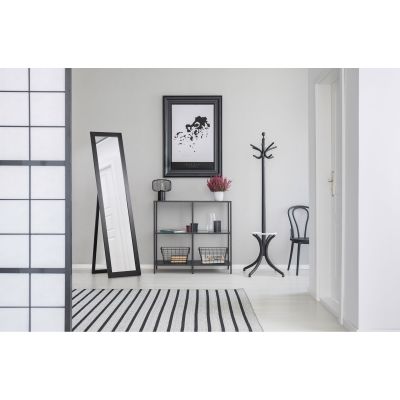 Spiegel Tina in Schwarz, in einem eingerichteten Raum im Nutzungskontext; zu sehen ist die schmale rechteckige Spiegelfläche mit rückseitigem Standfuß; Maße ca. 40 x 160 x 3,5 cm.