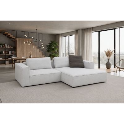 Die weiße Eckgarnitur mit ca. 300 x 188 cm Stellmaß ist in einem hellen Wohnambiente dargestellt. Zwei große Rückenkissen gehören zur Couch, zusätzlich ist ein dunkles Dekokissen zu sehen.