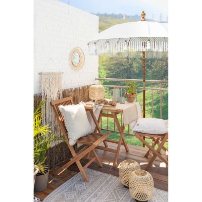 Klappstuhl aus Holz auf einem Balkon neben einem Tisch mit Pflanzen im Hintergrund
