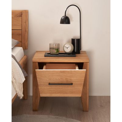 Nachttisch aus Holz mit geöffneter Schublade neben einem Bett im Schlafzimmer