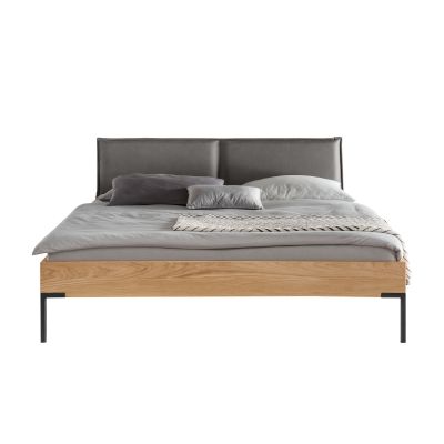 Bett mit gepolstertem Kopfteil grauer Bettwäsche Holzrahmen und schwarzen Metallfüßen in frontaler Ansicht