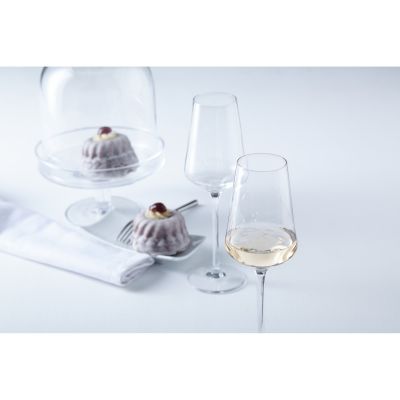 Zwei Weißweingläser neben kleinen Desserts auf hellem Tisch