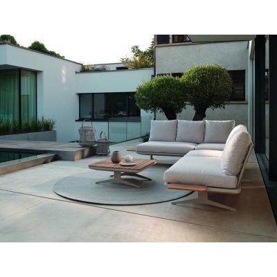 Outdoor Sitzgruppe mit Sofa, Sessel und niedrigem Tisch, aufgestellt auf einer Terrasse neben einem Pool vor einem Wohngebäude.