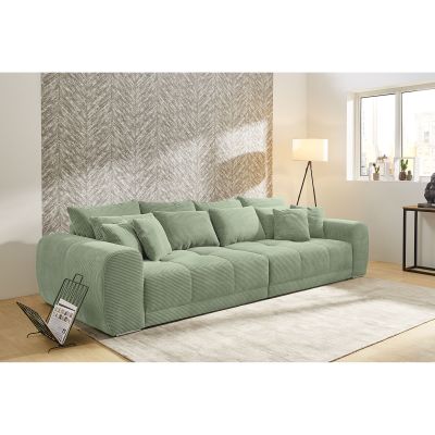Großes grünes Cordsofa mit vielen Kissen in modern eingerichteter Wohnlandschaft mit Teppich und Stehlampe
