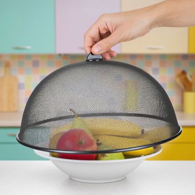 Schwarze Speisenetzhaube wird über eine Schale mit Obst auf einem Tisch gehalten