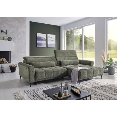 Helles Wohnzimmer mit großem Ecksofa in grünem Cordstoff, dekoriert mit Teppich, Pflanzen und Wandbildern.