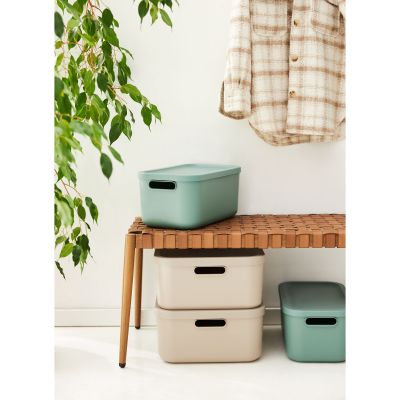 Aufbewahrungsboxen aus Kunststoff neben einem Möbelstück in einem Wohnbereich