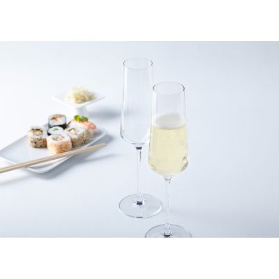 Zwei Sektgläser eines gefüllt mit Schaumwein neben Sushi auf hellem Tisch