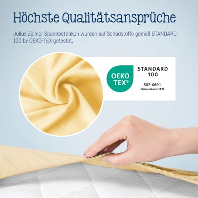 Nahaufnahme gelber Jersey-Stoff mit OEKO-TEX Logo und Hand, die das Spannbettlaken über eine Matratze zieht