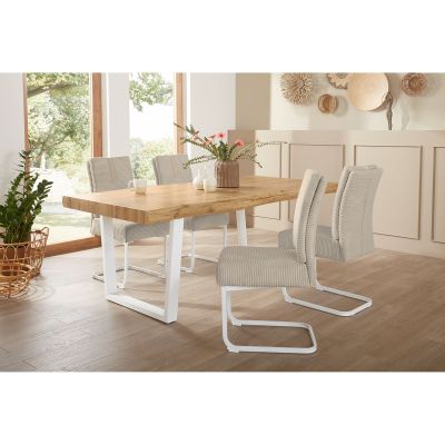 Helles Esszimmer mit großem Esstisch aus Holz und weißen Metallbeinen, dekoriert mit Stühlen und Accessoires.