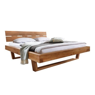 Doppelbett aus massivem Holz mit breitem Bettrahmen und geneigtem Kopfteil vor hellem Hintergrund