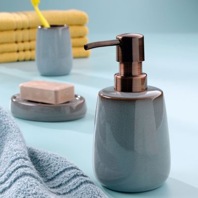 Nebelblaue Seifenschale und passender Seifenspender auf einer hellblauen Ablage neben Handtuch, Becher und weiteren Badaccessoires