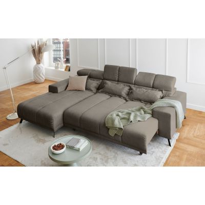Hellgraues Ecksofa mit Ottomane links und ausgezogener Liegefläche in einem hellen Wohnzimmer mit Teppich und Couchtisch