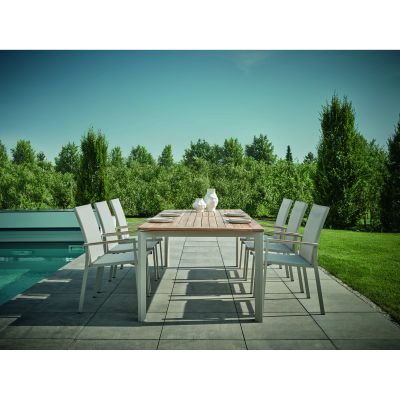 Rechteckiger Gartentisch mit mehreren Stühlen, aufgestellt auf einer Terrasse neben einem Pool, im Hintergrund Rasenfläche und Bäume.