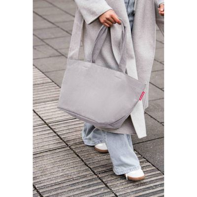 Shopper von Reisenthel, Modell Shopper M, in Hellgrau aus geripptem Cord, von einer Person an den Tragegriffen getragen.