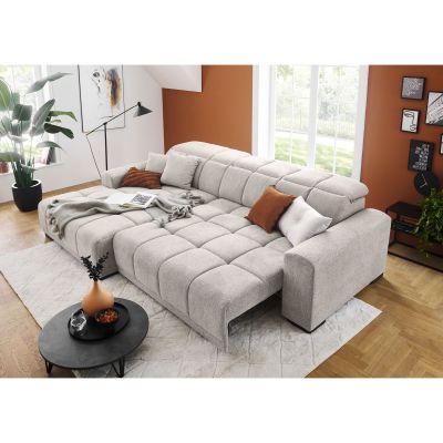 Silbergraues Schlafsofa mit vollständig erweiterter Liegefläche, verstellbaren Kopfstützen, Kissen und Decke in einem Wohnzimmer mit großen Fenstern