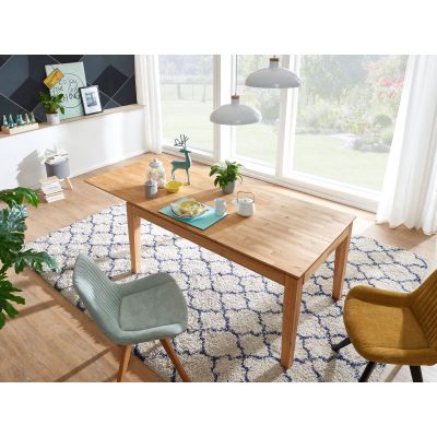 Ausziehbarer Esstisch aus Holz in einem Esszimmer mit Teppich, Stühlen und großen Fenstern