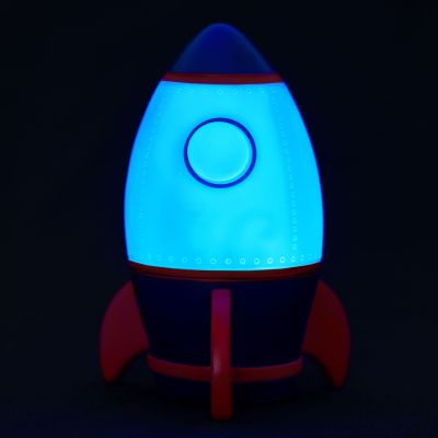 Nachtlicht in Raketenform, vor schwarzem Hintergrund blau leuchtend gezeigt.