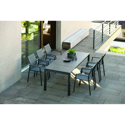 Outdoor-Esstisch mit mehreren Stühlen auf einer Steinterrasse vor einer Hausfassade