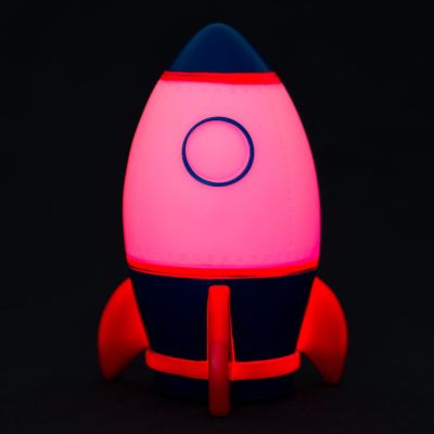 Nachtlicht in Raketenform, vor schwarzem Hintergrund rosa bis rot leuchtend gezeigt.