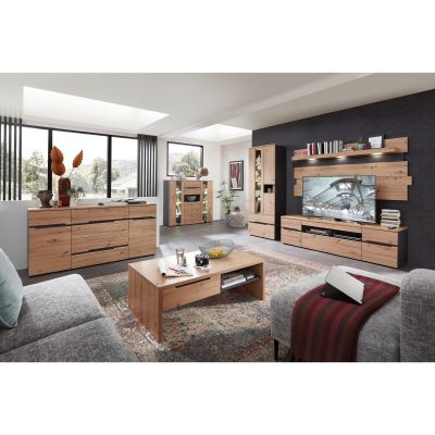 Großes Wohnzimmer mit Sideboard links, Vitrinen mit Beleuchtung im Hintergrund, TV-Wand rechts und einem Holzcouchtisch in der Mitte