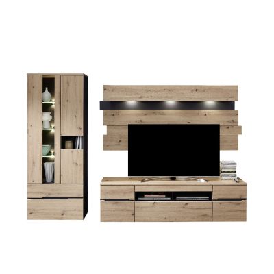 Wohnzimmeransicht mit einer Wohnwand in heller Holzoptik. Links steht eine Vitrine mit offenen und geschlossenen Fächern sowie Beleuchtung. In der Mitte befinden sich ein TV-Lowboard und dahinter versetzte Holzpaneele mit einem Wandboard und Beleuchtung. 