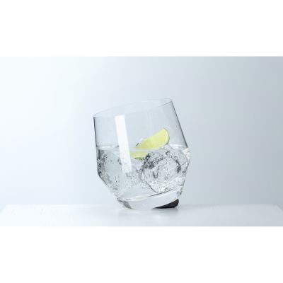Schräg stehendes Trinkglas mit Eiswürfeln und Limettenscheibe