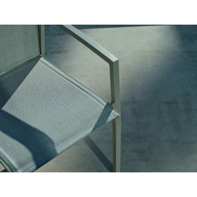 Ein Gartenstuhl mit heller textiler Sitzfläche, auf der Terrasse im Sonnenlicht mit deutlichem Schattenwurf.