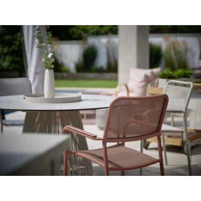 Gartenstuhl mit Armlehnen an einem Tisch im überdachten Außenbereich