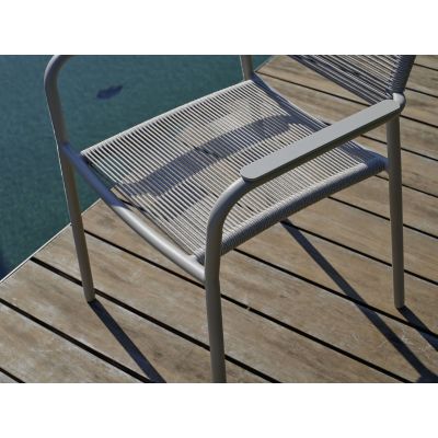 Geflochtene Sitzfläche eines Gartenstuhls auf Holzdeck neben Wasserfläche