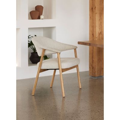 Moderner Stuhl mit Eichenholzgestell und heller Stoffpolsterung, platziert in einem minimalistischen Wohnraum