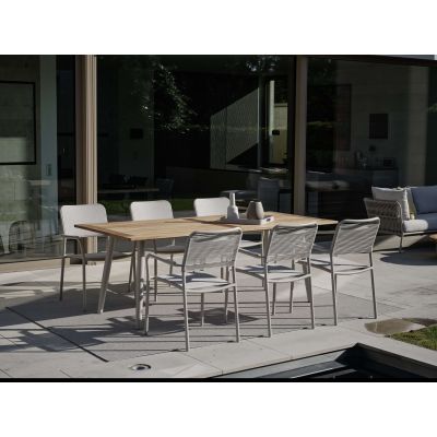 Mehrere Gartenstühle an rechteckigem Tisch auf Terrasse vor Glasfassade