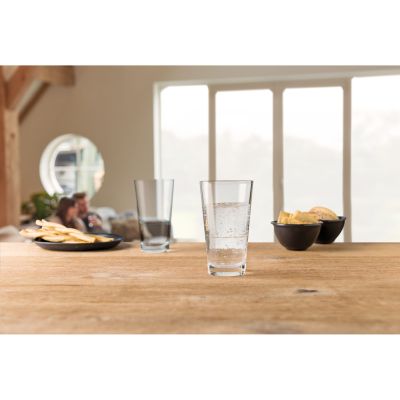Zwei Trinkgläser auf einem Holztisch eines mit Wasser gefüllt im Hintergrund Snacks und Wohnraum